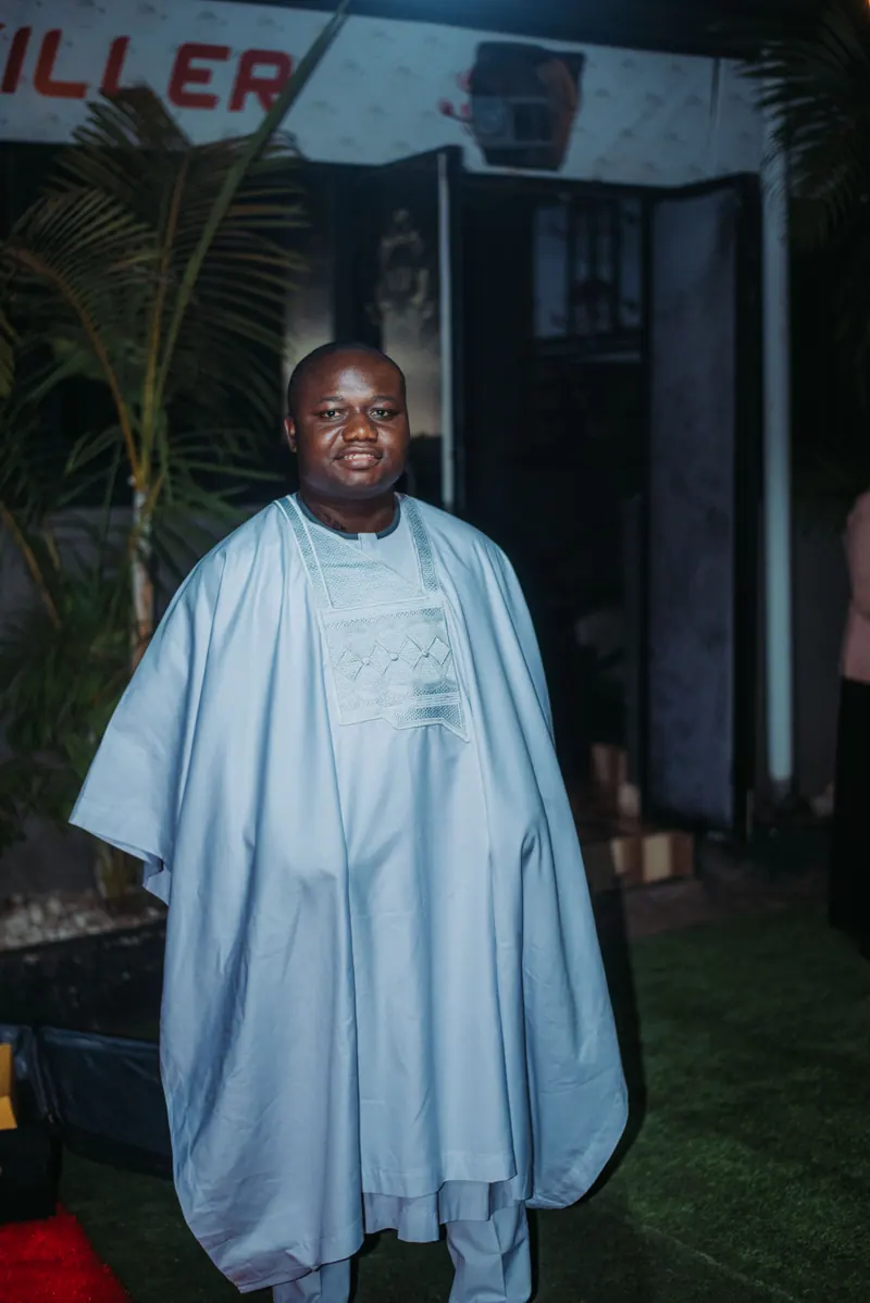 A man in a pale blue agbada stands on the lawn before the awards night