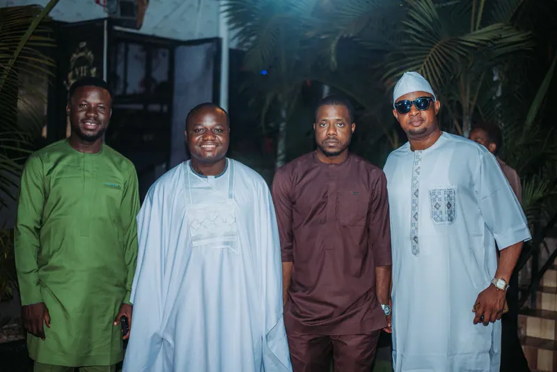 Four men in green, pale blue, maroon and white traditional outfits stand together at the awards night
