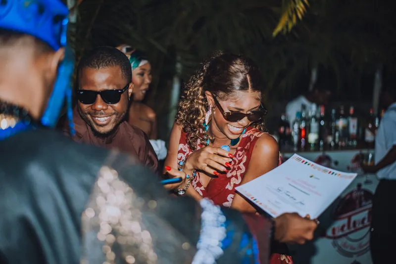 A woman in sunglasses collects her certificate while a man beside her grins