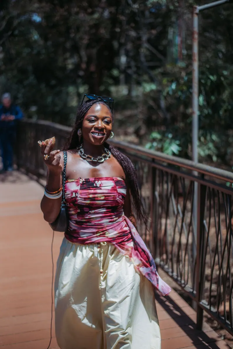 A woman in a maroon print top and cream skirt walks along the Giraffe Centre boardwalk
