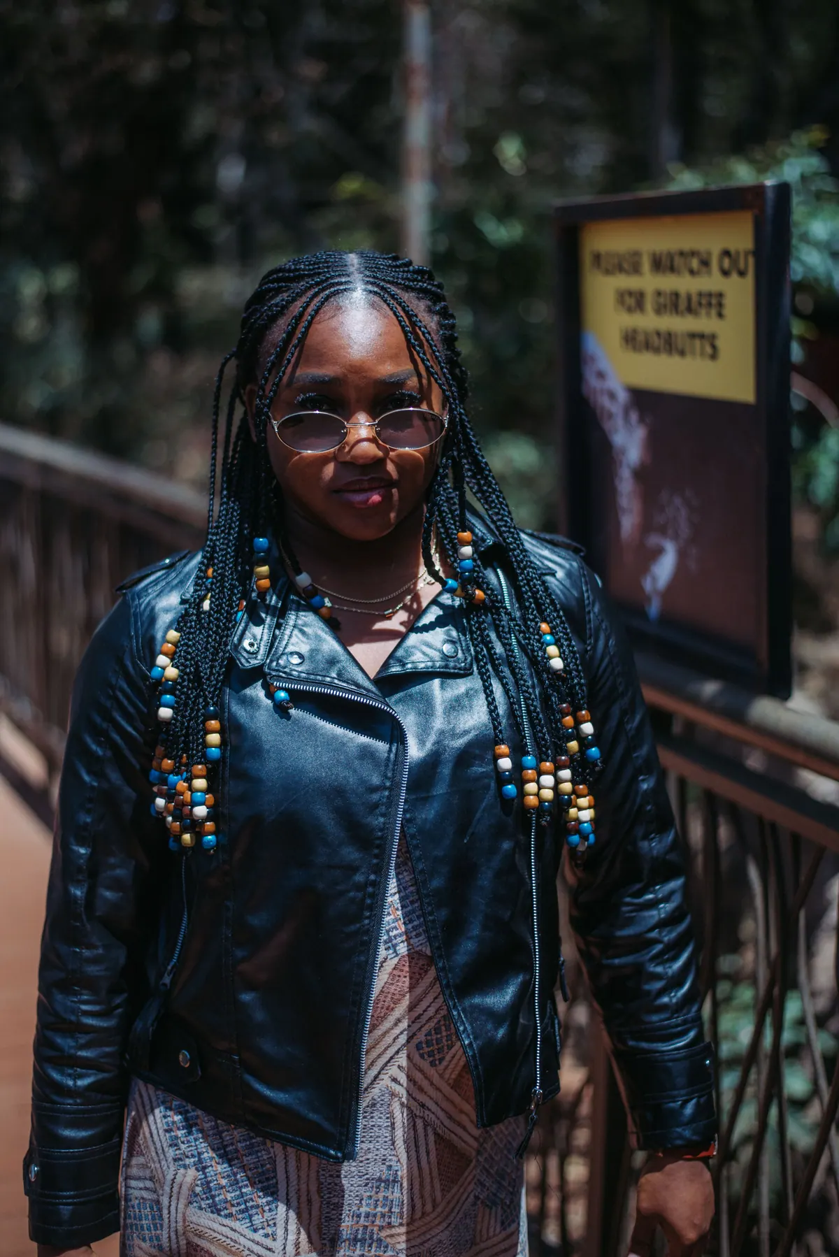 A woman in sunglasses and a black leather jacket stands on the boardwalk