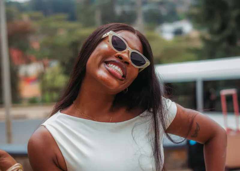 A woman in white cat-eye sunglasses tilts her head and laughs