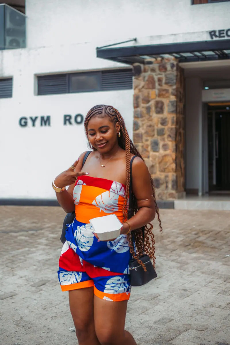 A woman in an orange and blue print shorts set stands outside the hotel